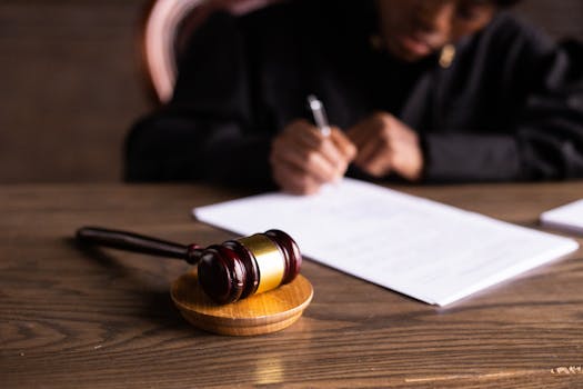 pexels photo 6077447 6077447 Judge signing documents at desk with focus on gavel, representing law and justice.